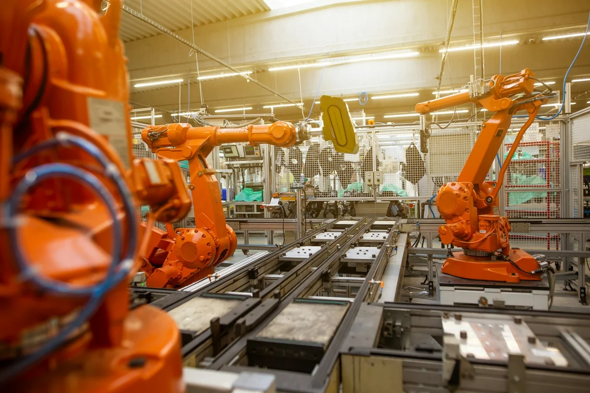 Photograph: Simon Kadula / Unsplash Industrial robotic arms operating along an automated factory production line